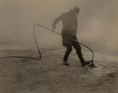 (Man tarring a road)
