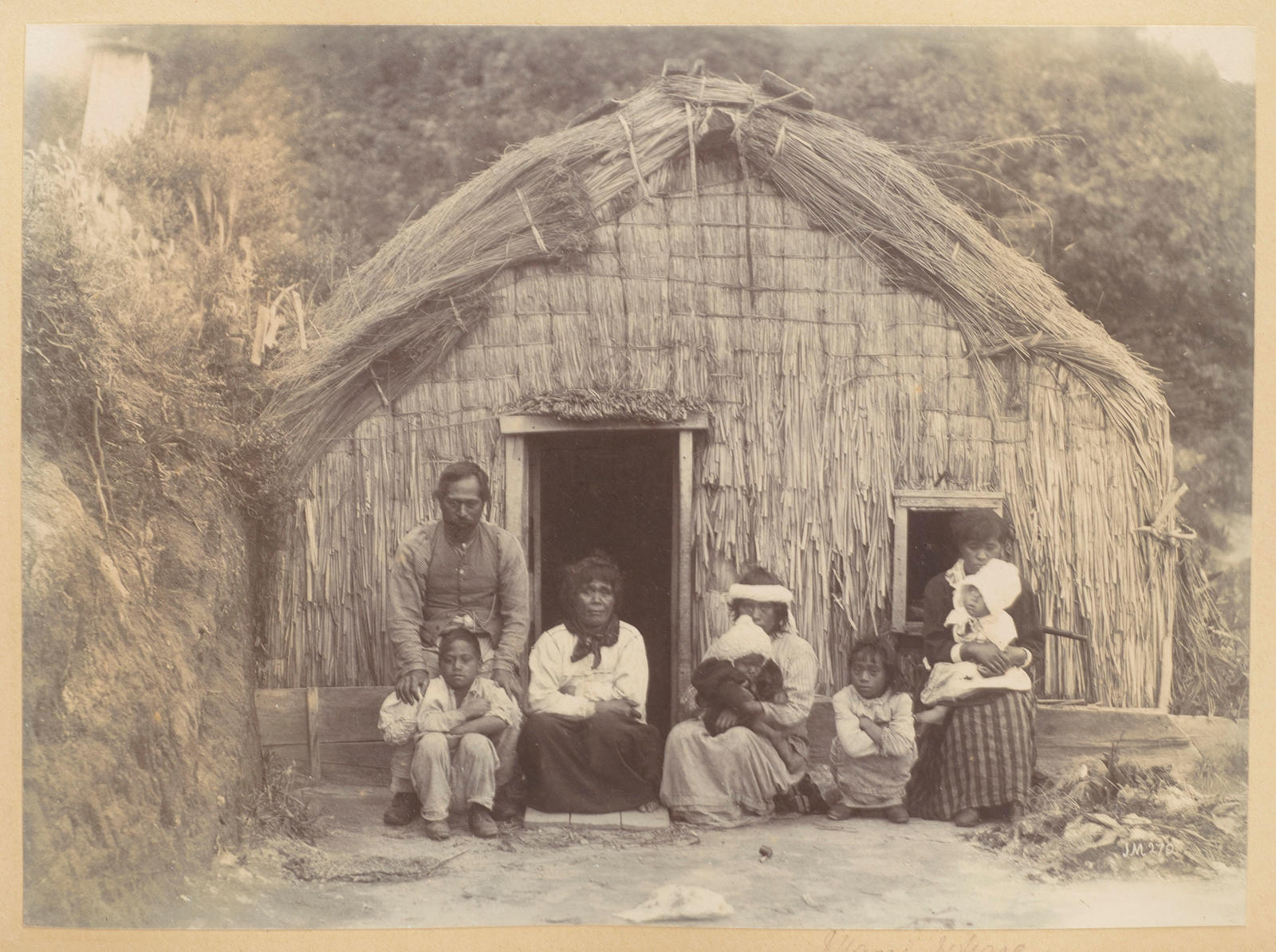 Maori family in front of whare