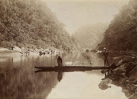 River scene with two figures in outrigger canoe