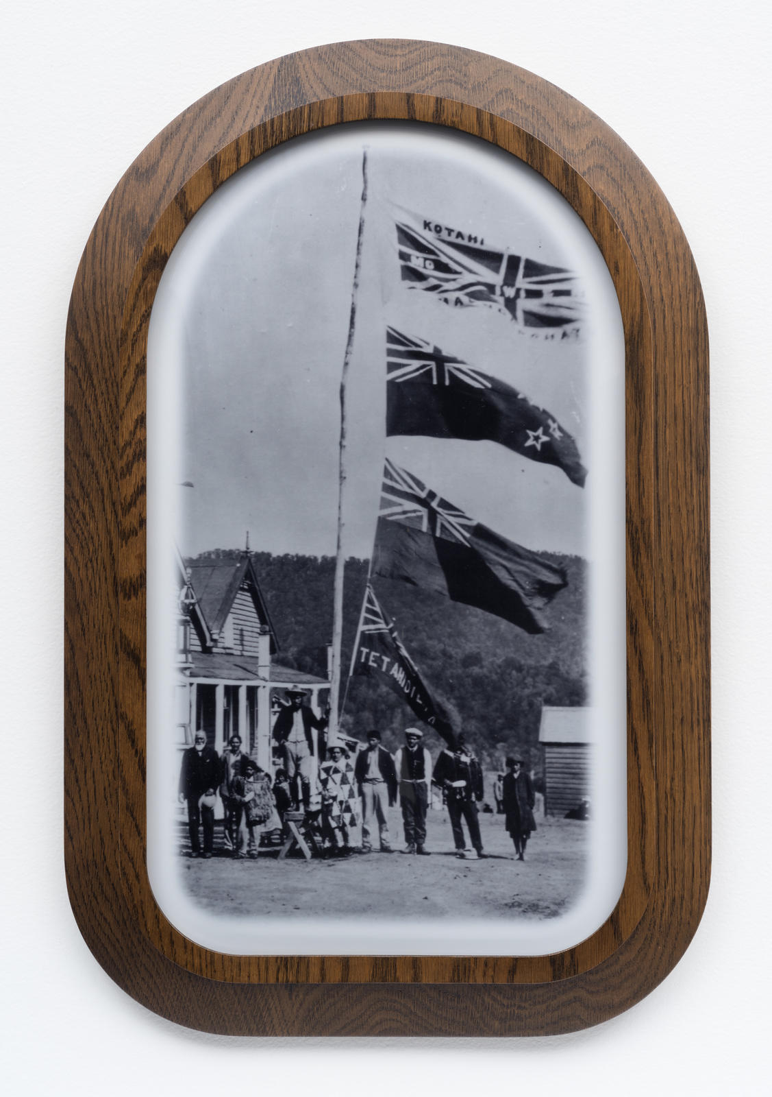 Kōtahitanga, Maungapōhatu (1908). Rua Kenana’s followers with 4 flags flying outside his residence. Top flag confiscated by police in 1916. It reads, “Two races, One People, Equal Rights”. Whakatāne Museum Photographic Archive–P10737. Photographer George