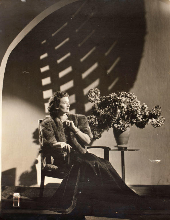 (Woman in fur jacket seated with hydrangeas)