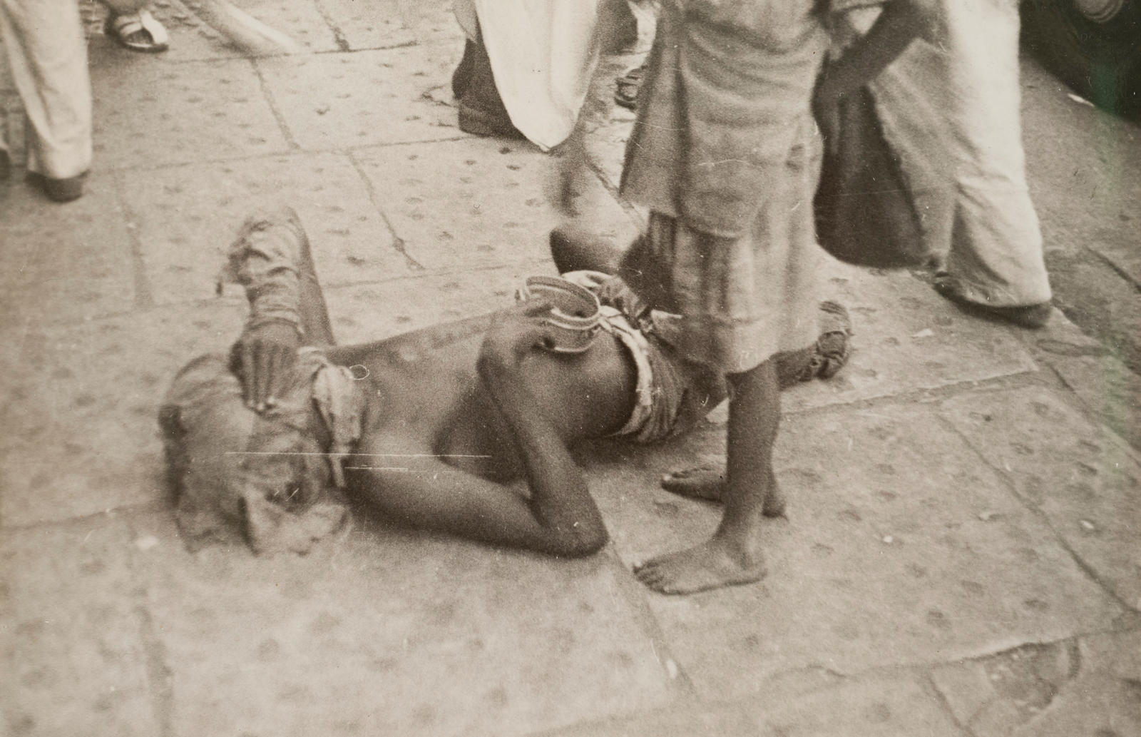 Bombay (beggar on ground, with face covered)