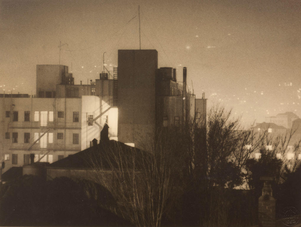 (Night scene of buildings and city beyond)